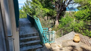 Un escalier menant à une terrasse d’où l’on peut admirer des arbres et un plan d’eau.