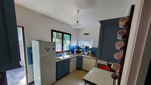 Une cuisine compacte équipée d’un réfrigérateur, d’un four à micro-ondes, d’un évier et d’une petite table à manger.