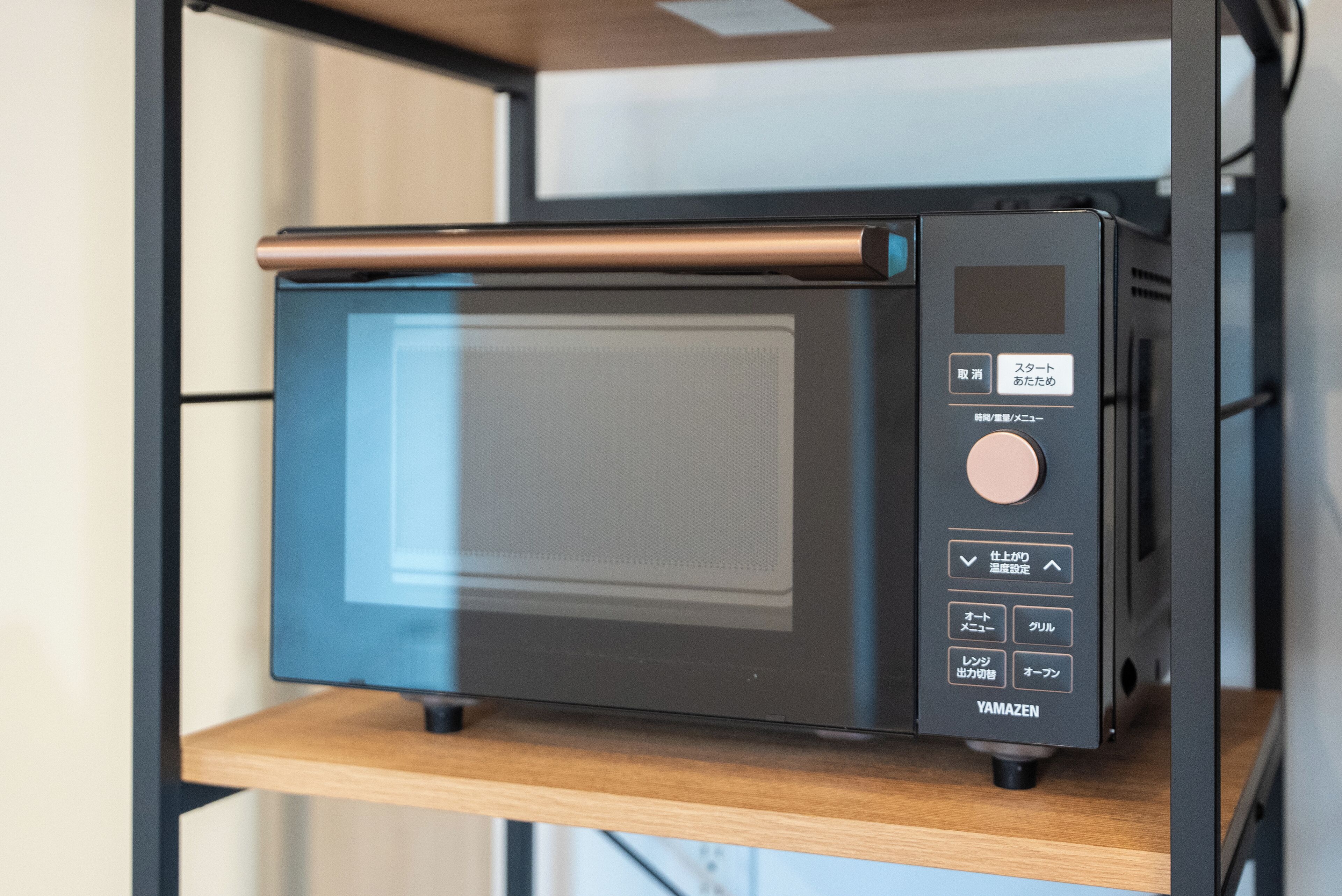 A compact microwave oven with a digital display and control buttons, placed on a wooden shelf.