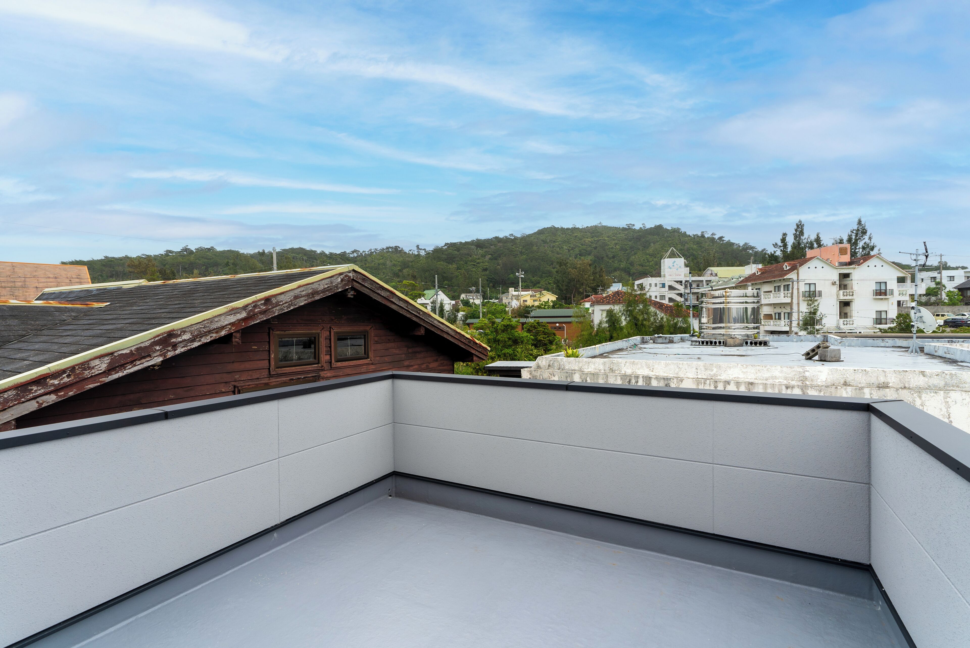 Una terraza en la azotea con vistas a edificios circundantes y una colina al fondo.