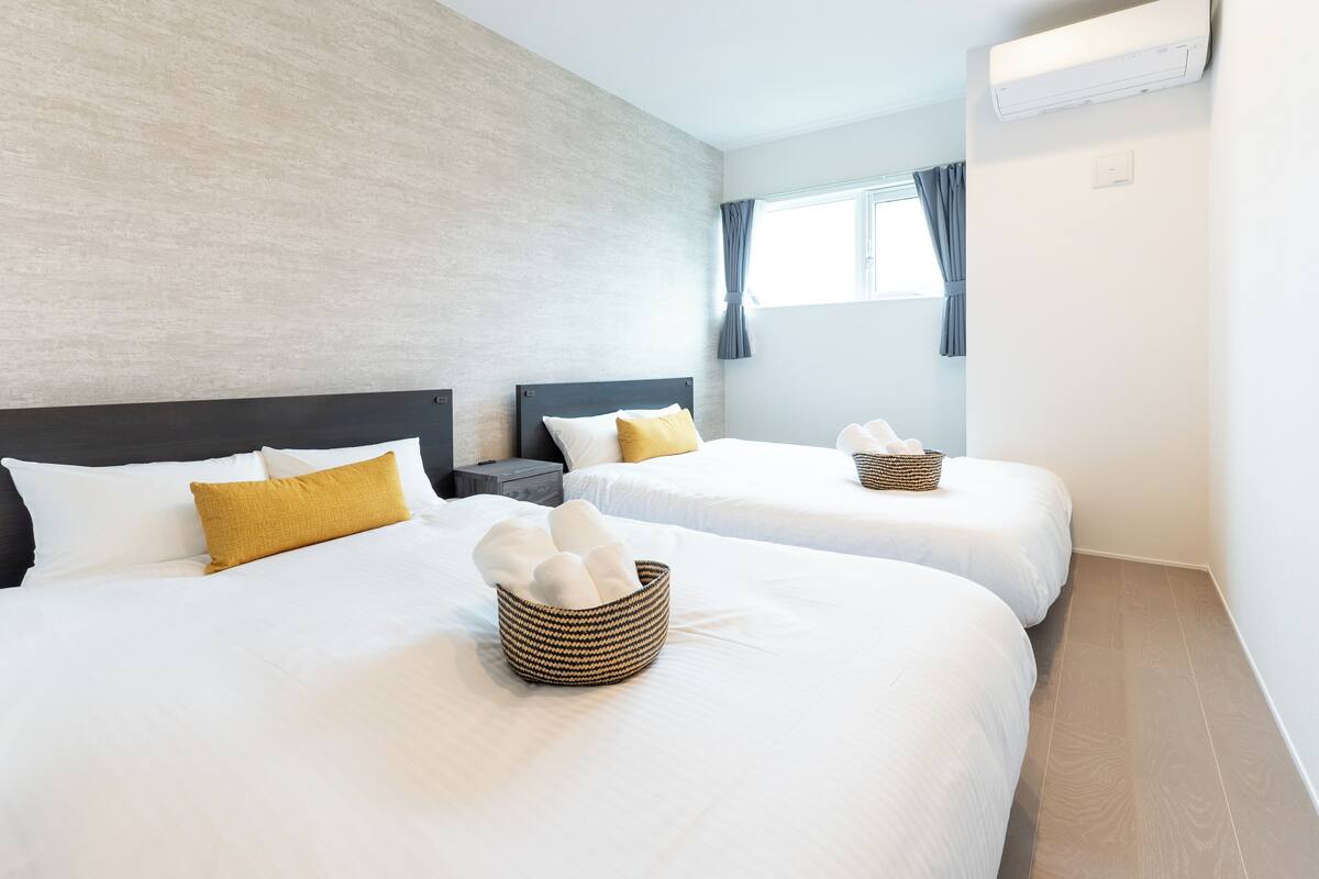 A hotel room with two beds, each with white bedding and a brown woven basket on the bed.