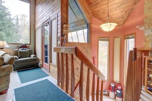 A cozy cabin interior with a wooden staircase, a sofa, a lamp, and a snowman decoration.