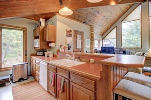 A kitchen with wooden cabinets, a large island with a sink, and a dining area with a blue couch.