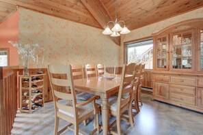 A wooden dining room with a table and chairs, a wine rack, and a cabinet with glass doors. - Alaskan Cabin Escape w a Hot Tub (Anchorage)
