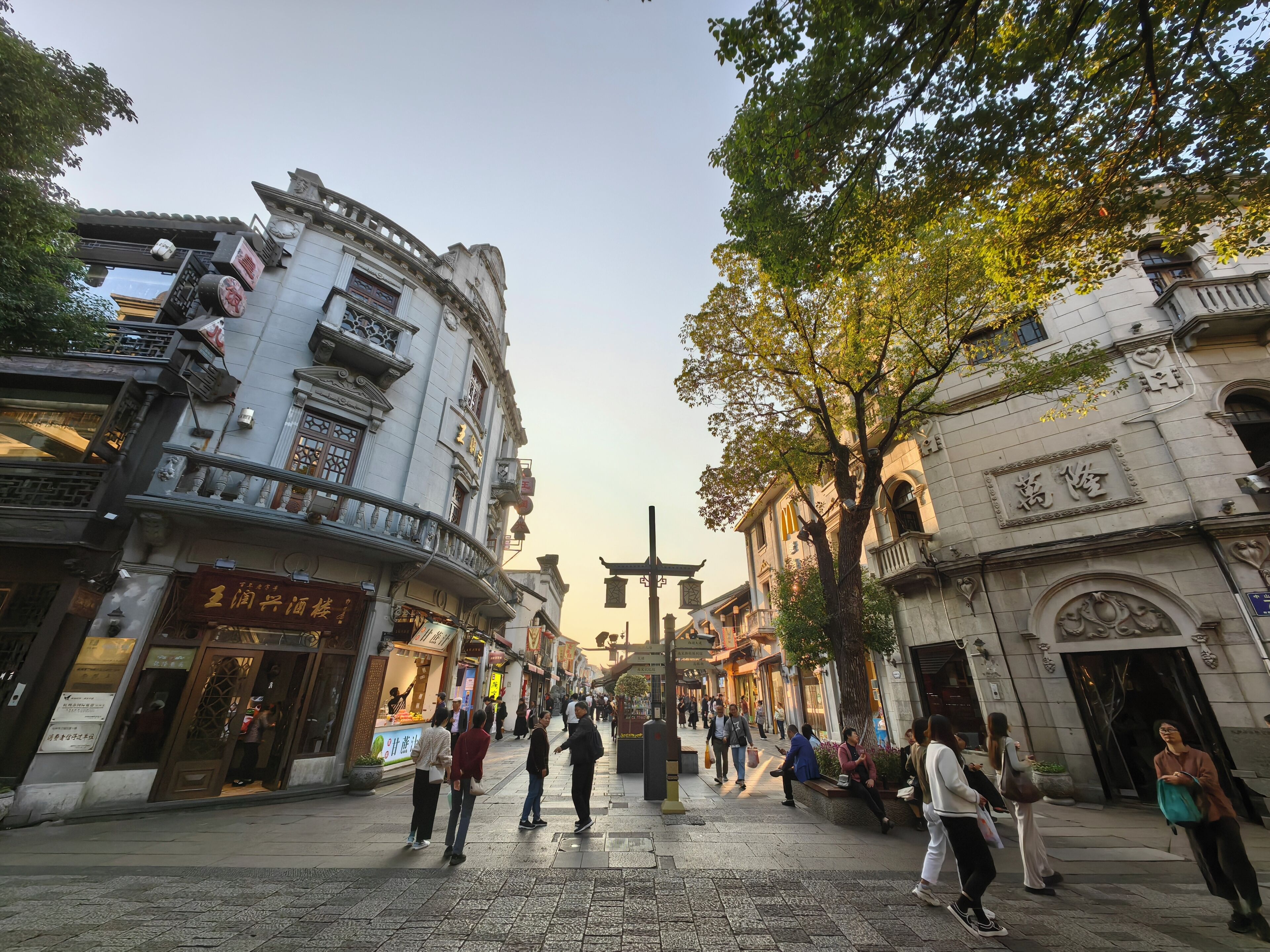 Une rue typique, bordée de bâtiments historiques, avec une zone piétonne centrale et des passants.