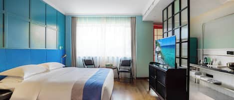 A hotel room with a large bed, a desk, a chair, a television, and a bathroom.