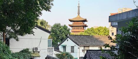 A narrow alleyway with traditional architecture, a pagoda in the background, and a sign with Chinese characters.