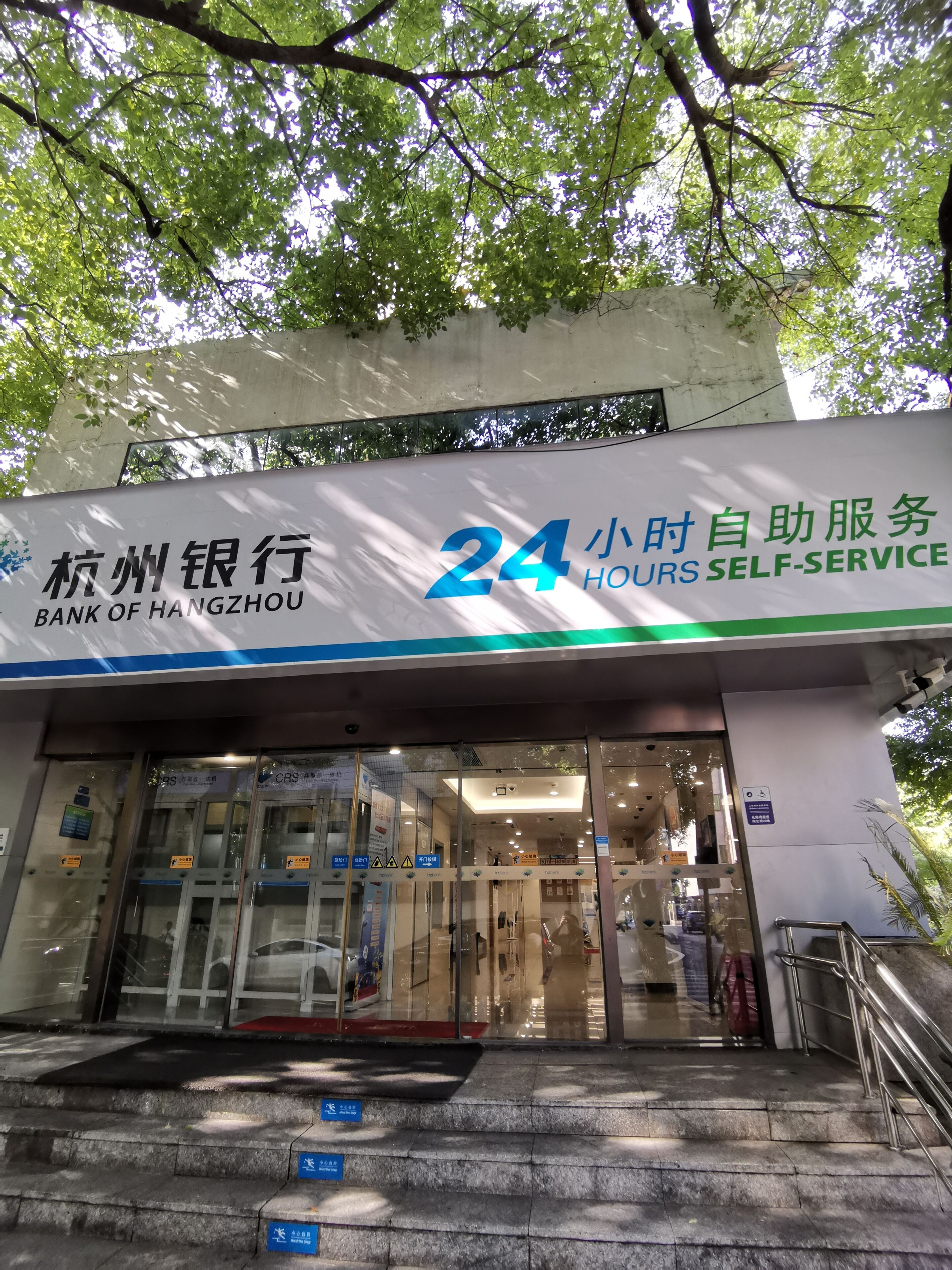 La façade de la Banque de Hangzhou, avec une enseigne indiquant un service de libre-service disponible 24 heures sur 24.