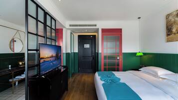 A hotel room with a bed, a television, a desk, and a green wall.