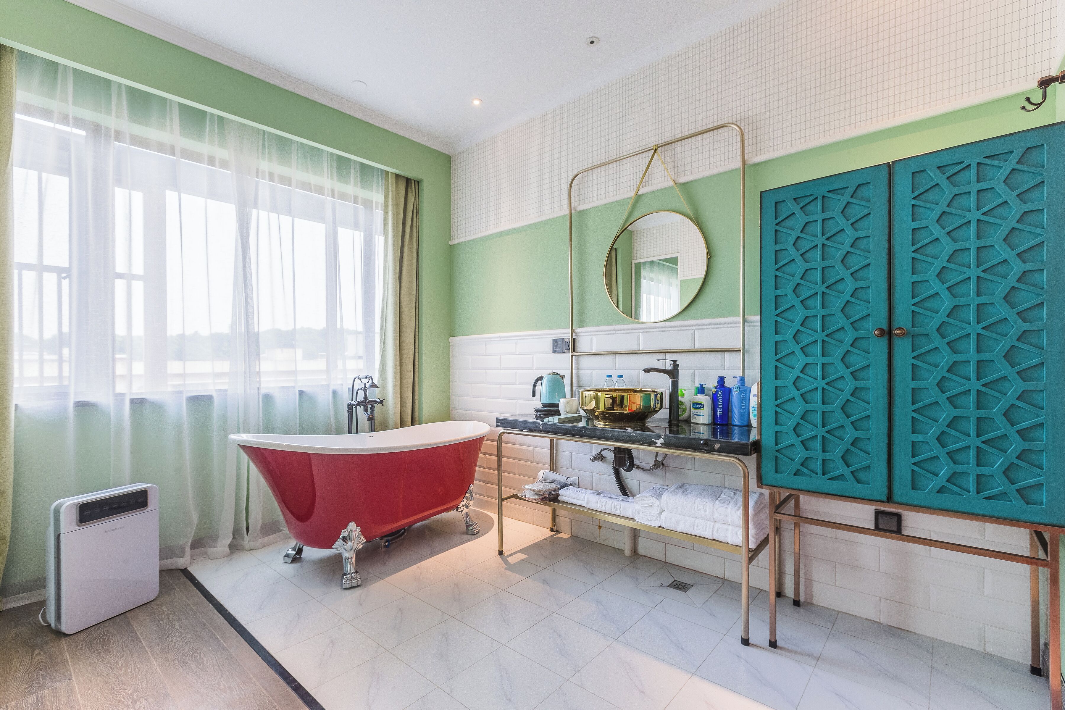 A bathroom with a red clawfoot bathtub, a white toilet, and a sink with a gold-colored vanity.