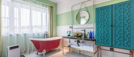 A bathroom with a red clawfoot bathtub, a white toilet, and a sink with a gold-colored vanity.