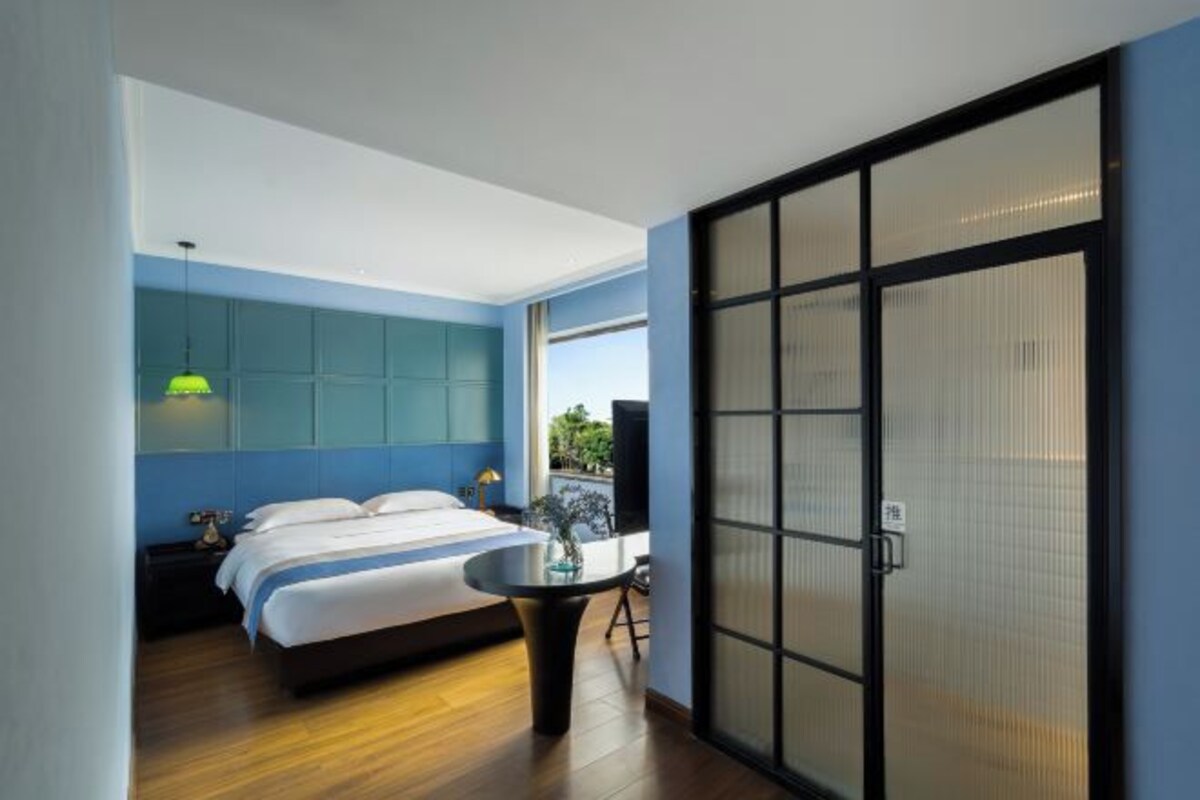 A modern bedroom with a bed, bedside table, and a view through a sliding door.