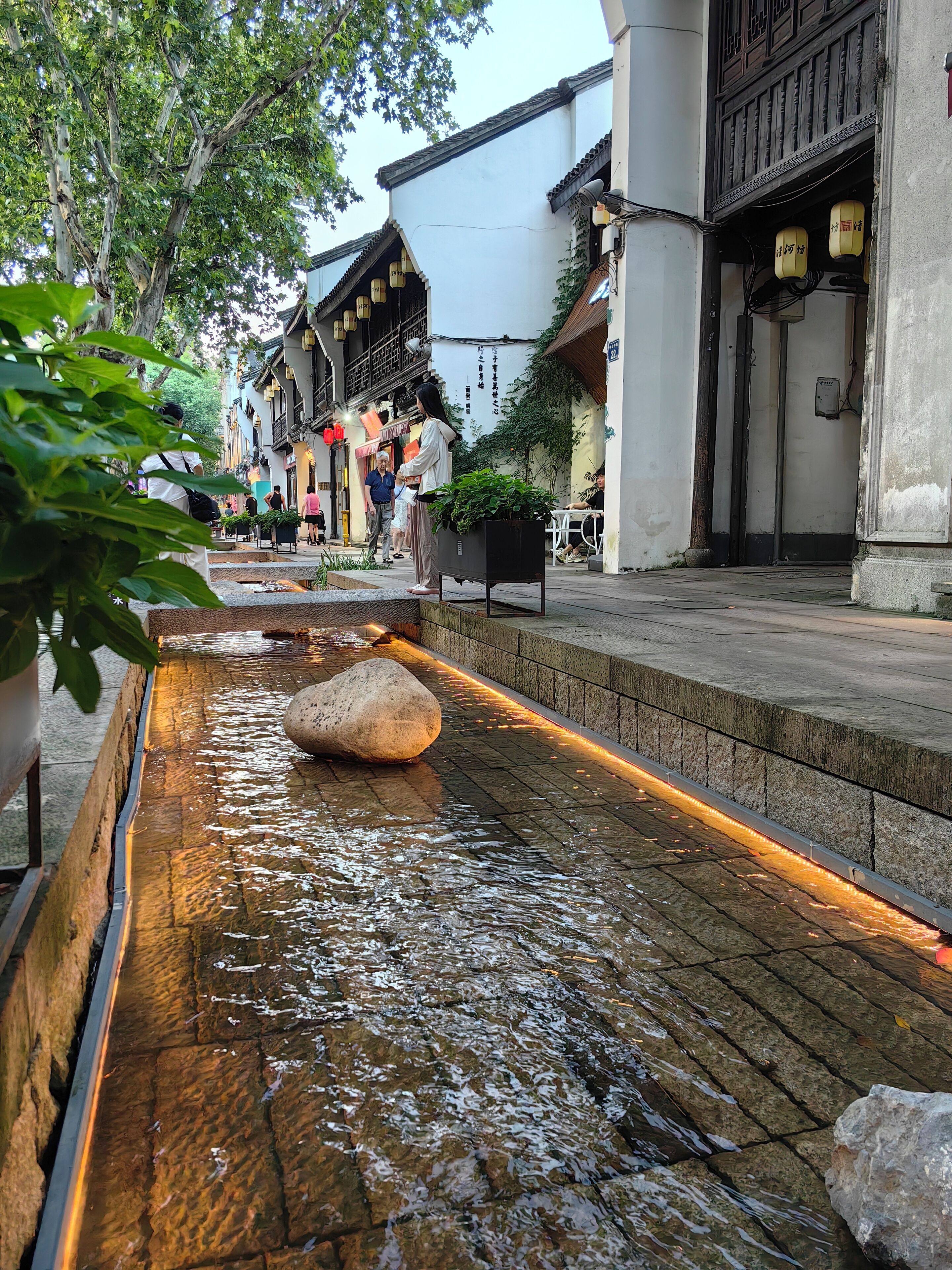 Una calle tradicional con una fuente, adoquinado de piedra y edificios de arquitectura típica.