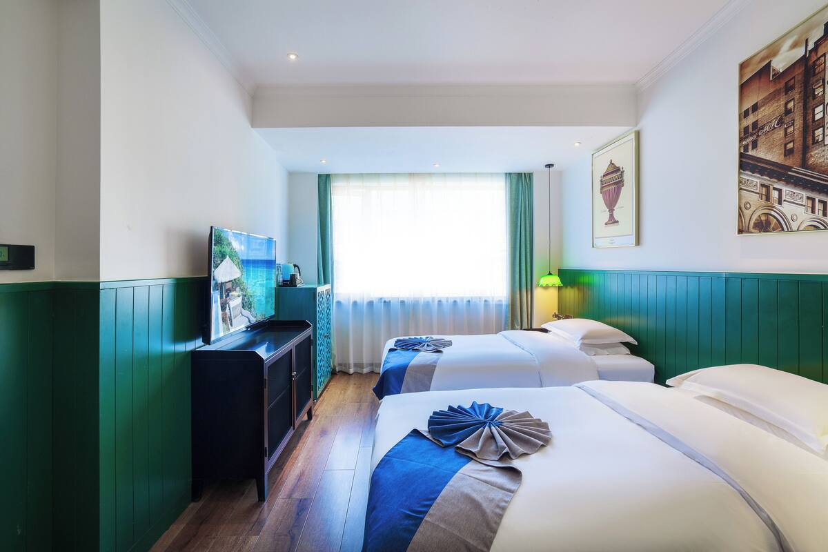 Habitación de hotel con dos camas, un escritorio y una televisión.