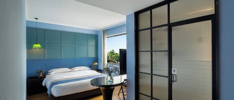 A modern bedroom with a bed, bedside table, lamp, and a view through a sliding door.