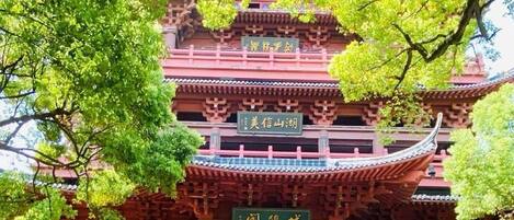 A traditional multi-tiered building with a stone wall entrance and signage indicating different sections.