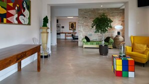 A spacious living area with a wooden bench, a colorful abstract painting, a green sofa, a yellow armchair, and a Rubik's cube on a table. - Holiday home with pool, whirlpool and solarium (Perugia)