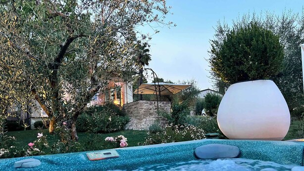 A hot tub with a stone wall and greenery in the background. - Holiday home with pool, whirlpool and solarium (Perugia)