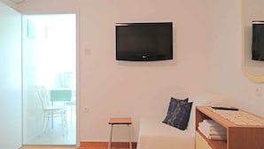 A room with a bed, a TV mounted on the wall, a small table, and a chair. - Studio near the Old Town (Krk)