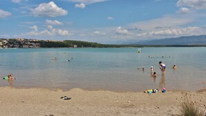 A beach with people swimming and sunbathing, a clear sky, and distant mountains. - Studio near the Old Town (Krk)