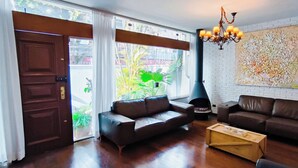 Uma sala de estar moderna com dois sofás de couro, uma mesa de centro de madeira, uma lareira e um grande quadro abstrato na parede.