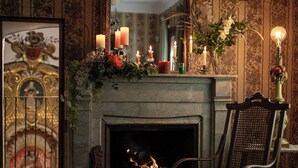 Una chimenea con velas encendidas, un sillón y un cuadro en la pared.