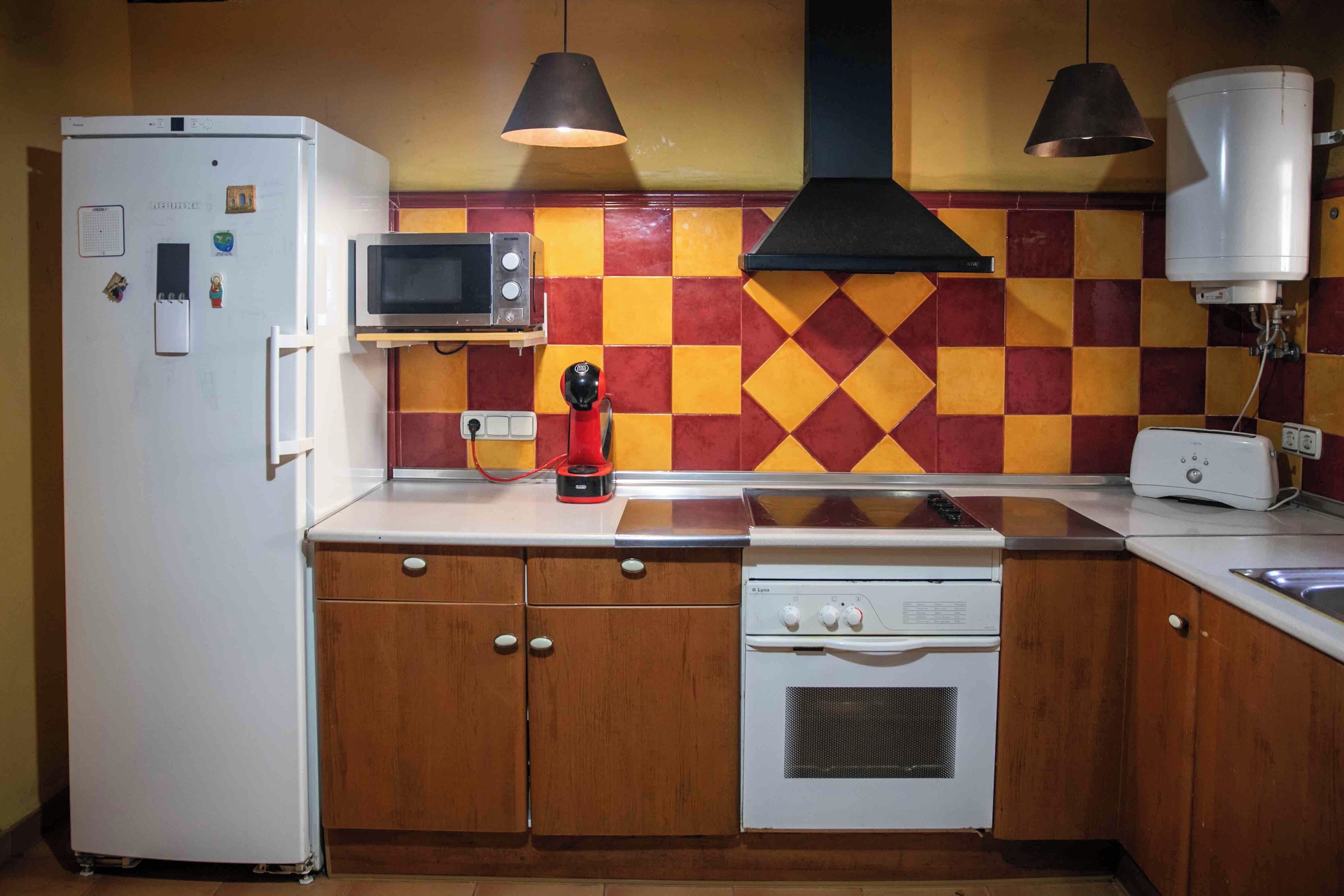 Eine kleine Küche mit Kühlschrank, Mikrowelle, Toaster und Herd.