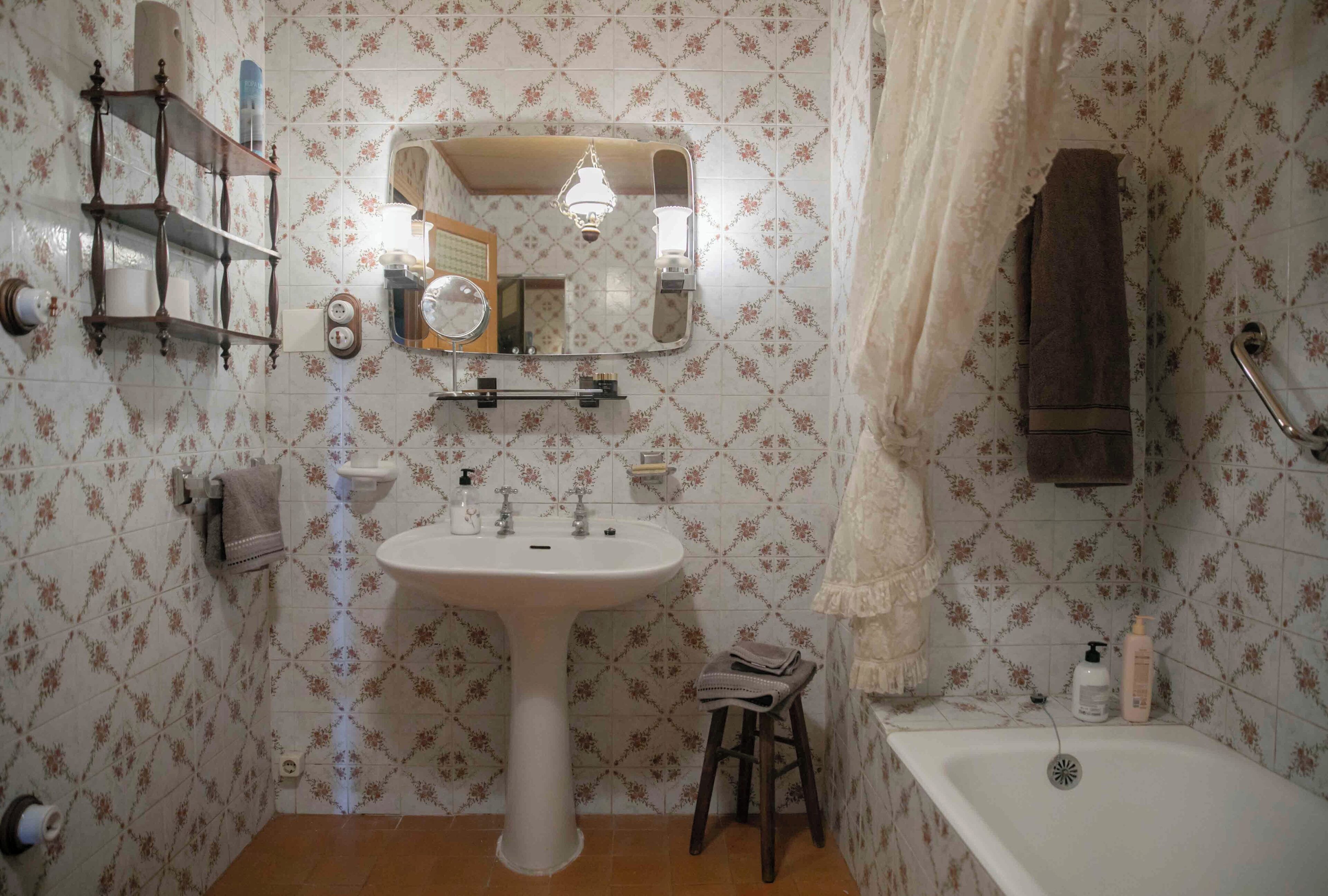 Un baño con lavamanos pedestal, espejo, perchero, cortina de ducha y ba ñera.