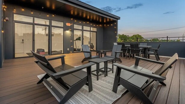 Eine Terrasse im Freien mit moderner Möbel, einem Glastür-Eingang und Lichterketten.