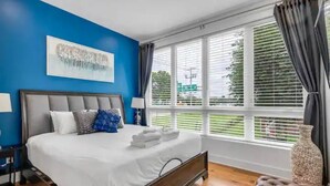 Ein Schlafzimmer mit einem großen Bett, einem Fenster mit Jalousien und Blick ins Freie.