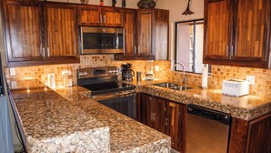 Eine Küche mit Granit-Arbeitsplatten, Holzschränken und modernen Edelstahlgeräten, inklusive Geschirrspüler.