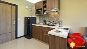 A modern kitchen with wooden cabinets, a black refrigerator, a microwave, and a coffee maker. - Naiharn Condominium 1 bedroom 36 sq. m. (Rawai)