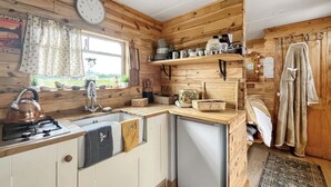 Een kleine keuken met houten wanden, een gootsteen, een fornuis en een raam met gordijnen.