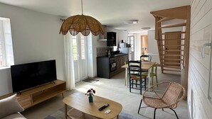 Una sala moderna con televisor de pantalla plana, un sofá, una mesa de centro y una zona de comedor con sillas.
