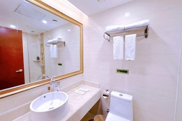 Une salle de bain avec un grand miroir, un lavabo, des toilettes et deux porte-serviettes.
