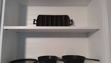 A kitchen with white cabinets and a black pan on the lower shelf.