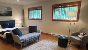 A bedroom with a bed, a sofa, a chair, a rug, and two windows. - A Seaside Jacuzzi Escape in Parksville, British Columbia, Canada (Parksville)