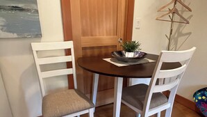 A dining area with a round table, two white chairs, and a wooden door. - A Seaside Jacuzzi Escape in Parksville, British Columbia, Canada (Parksville)