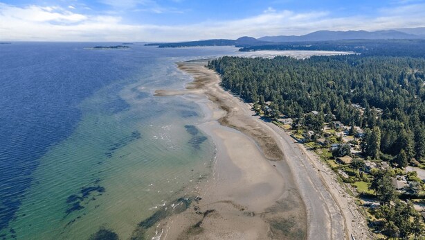 An aerial view of a coastal area with a sandy beach, dense forest, and a clear blue sky. - A Seaside Jacuzzi Escape in Parksville, British Columbia, Canada (Parksville)