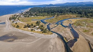 An aerial view of a coastal area with a river, forested hills, and a small settlement with houses and roads. - A Seaside Jacuzzi Escape in Parksville, British Columbia, Canada (Parksville)