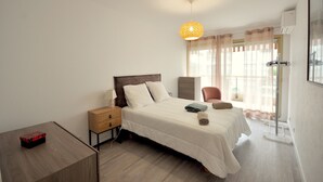 Un dormitorio ordenado con cama, mesita de noche y una lámpara colgante.