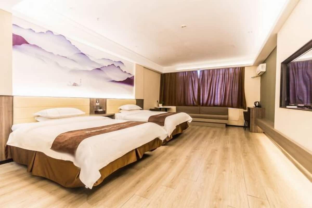 Camera d'albergo con due letti, un grande murale, un divano e una televisione.