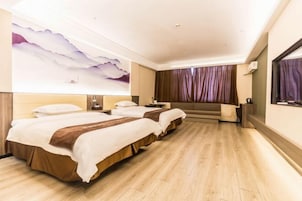 A hotel room with two beds, a large wall mural, a sofa, and a TV.
