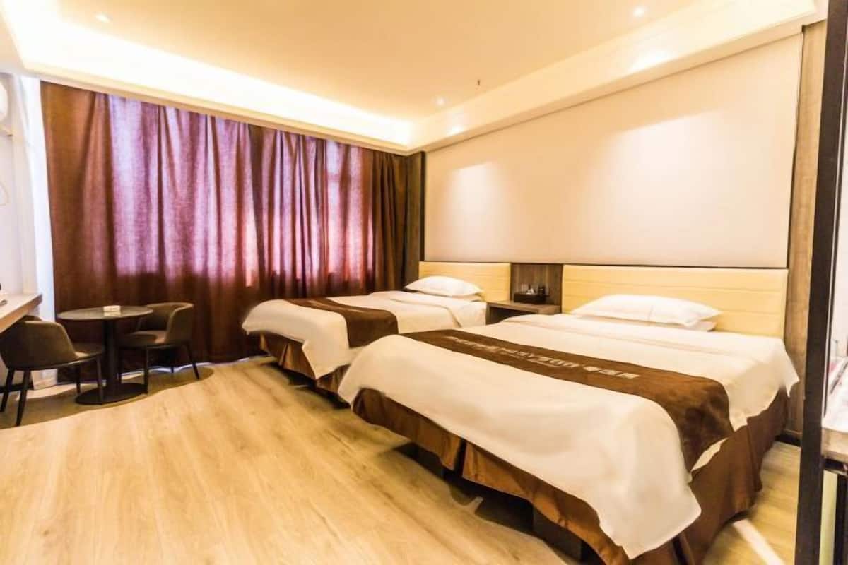 Una camera d'albergo con due letti, una scrivania e una sedia.