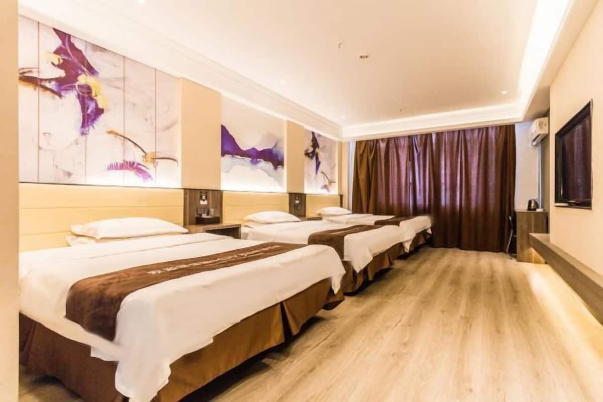 Camera d'albergo con tre letti allineati lungo una parete, un quadro astratto di grandi dimensioni sopra i letti e pavimento in legno.