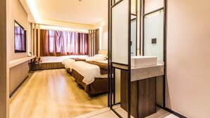 A hotel room with a wooden floor, two beds, a bedside table, a mirror, and a small sink. - Yanji Moka Boutique Hotel (Yanji)