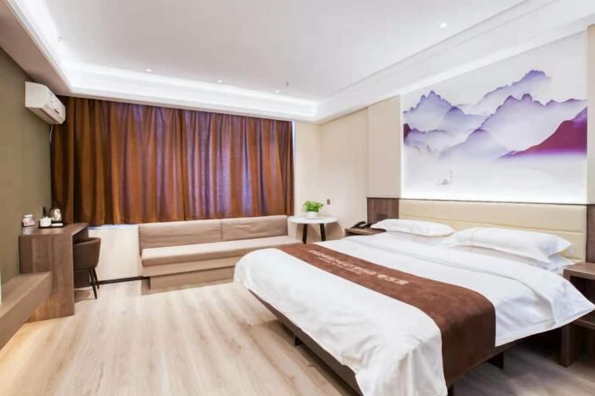 Una moderna camera d'albergo con un grande letto, un divano, una scrivania e una TV a parete.