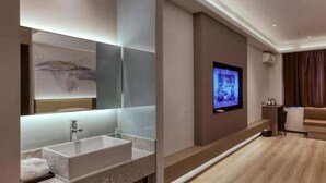 A modern bathroom with a large mirror, a white sink, and a television mounted on the wall. - Yanji Moka Boutique Hotel (Yanji)