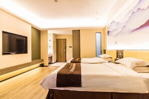 Ein Hotelzimmer mit zwei Betten, einem an der Wand befestigten Flachbildfernseher und einem großen Fenster mit Blick auf den Himmel.