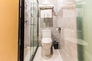 Ein modernes Badezimmer mit Duschkabine aus Glas, Toilette und Mülleimer.